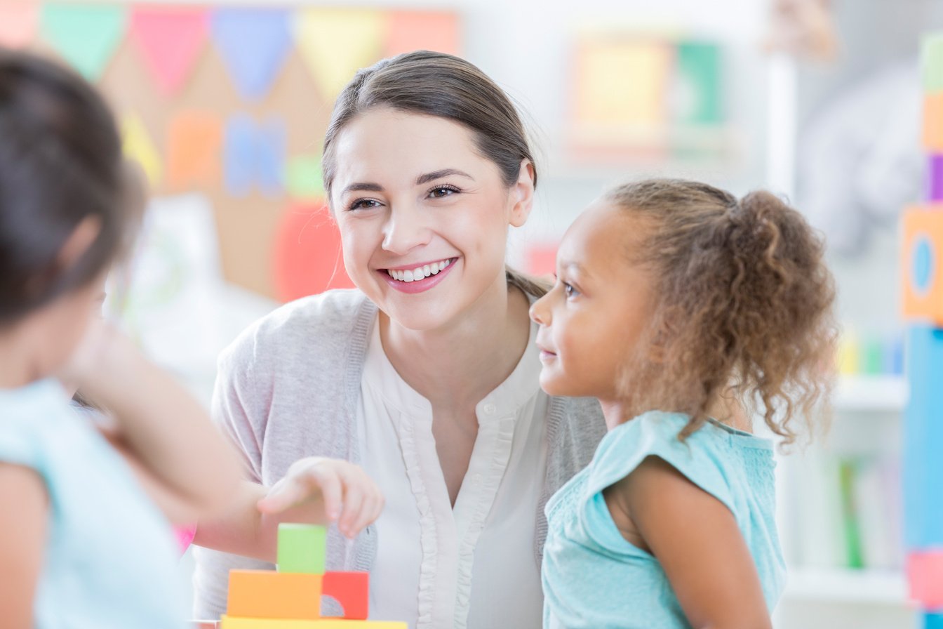 Attentive child care worker sits with children after school